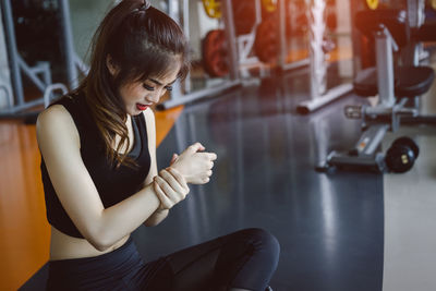 Young woman suffering from joint pain while exercising in gym