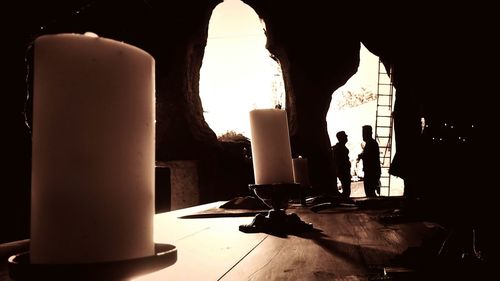 Silhouette of man with illuminated lamp on table