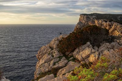 Rock formation by sea against sky