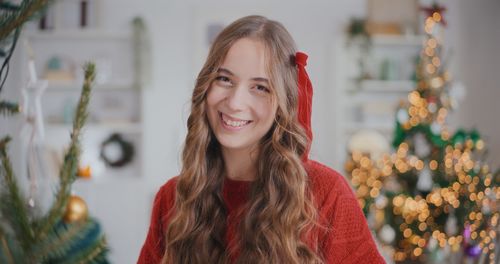 Portrait of smiling young woman standing against plants