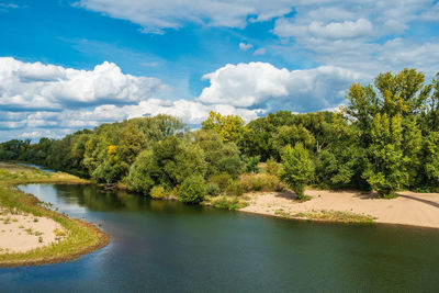 Scenic view of river by trees against sky