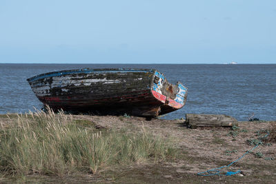 Abandoned boat on shore against sky