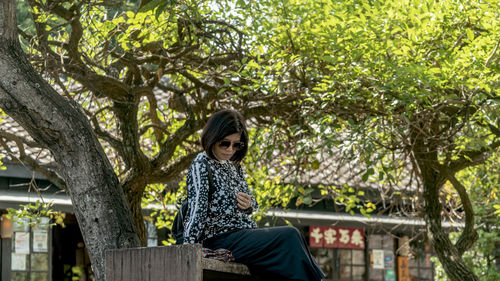 Young woman standing against trees