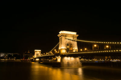 Low angle view of illuminated bridge over river at night