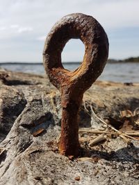 Close-up of rusty metal on beach against sky