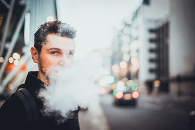 Close-up portrait of young man smoking cigarette in city