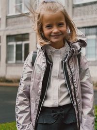 Portrait of young woman standing against building