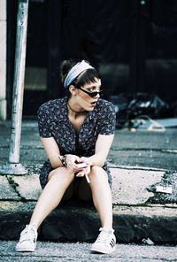 Full length of young woman using mobile phone while sitting outdoors