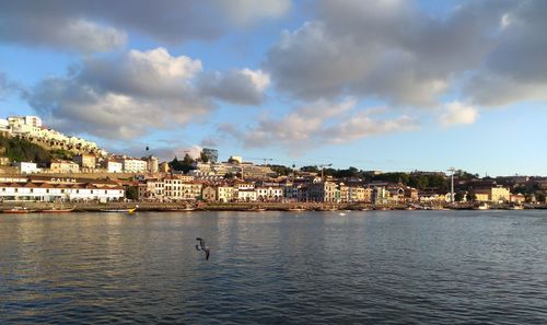 Buildings by river against sky in city