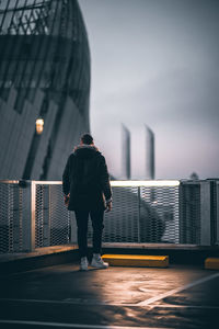 Rear view of man standing against buildings in city