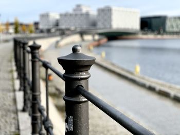 Close-up of railing by river in city