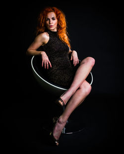 Portrait of young woman against black background