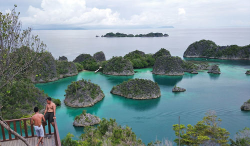 Panoramic view of people looking at sea against sky