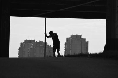 Silhouette man standing in city against clear sky