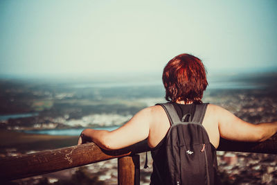 Rear view of woman looking at sea against cityscape