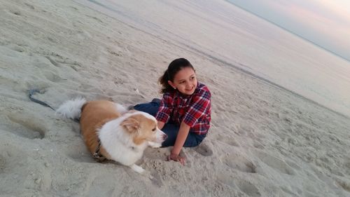 Portrait of woman with dog sitting on sand