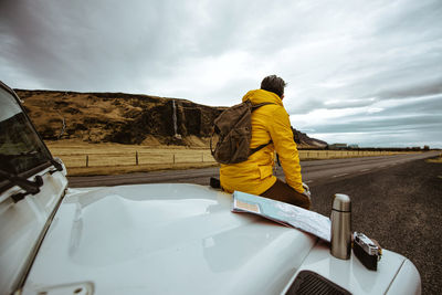 Rear view of man skateboarding on car against sky