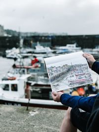 Midsection of man holding paper against sky