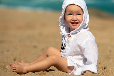 Portrait of cute girl sitting on sand at beach