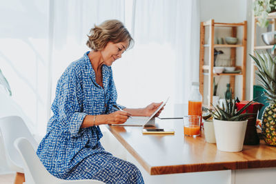 Side view of man using digital tablet while sitting on sofa at home