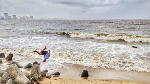 Full length of boy backflipping at beach