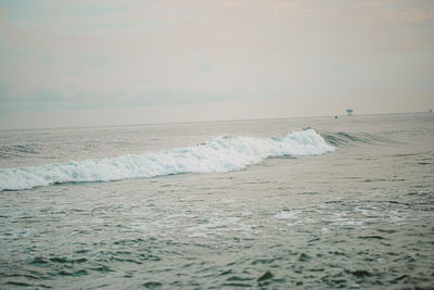 Waves rushing towards shore against sky