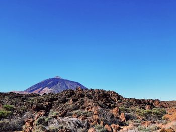 Scenic view of volcanic mountain against clear blue sky