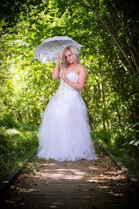 Happy woman standing by tree against plants