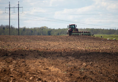 Tractor plowing the ground near power lines