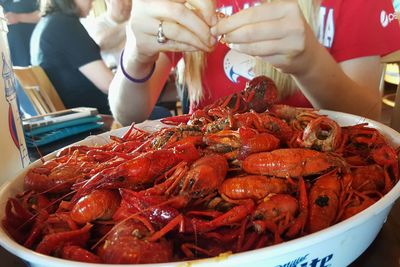 Midsection of woman sitting in front of cooked crawfish at restaurant