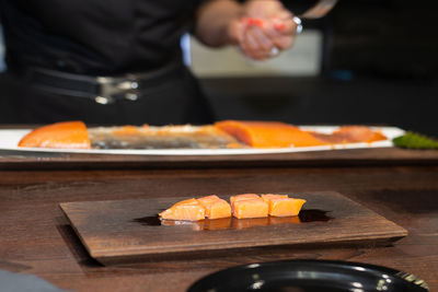 Chef slicing salmon on black wooden table in a restaurant.