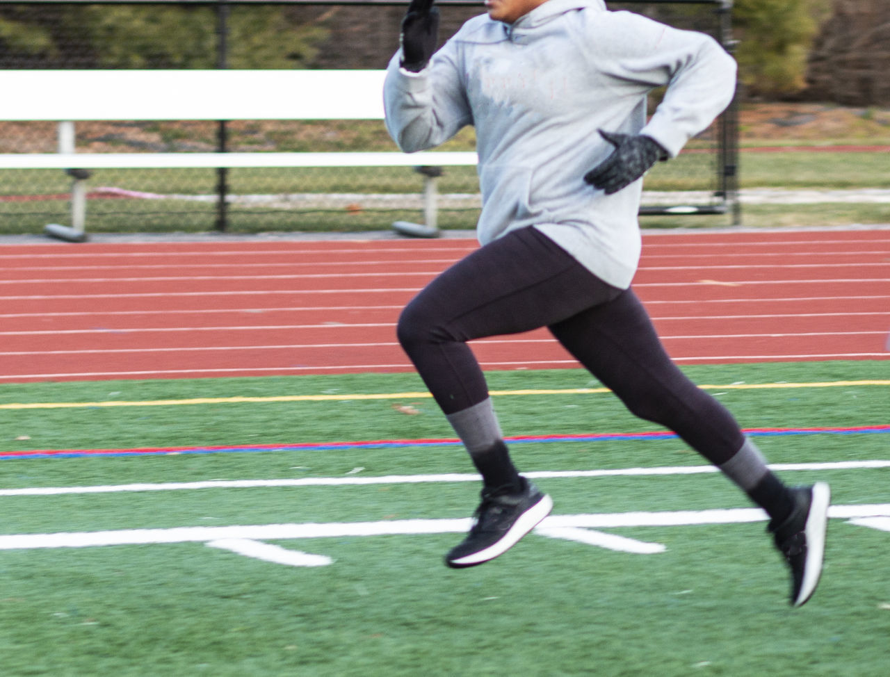 FULL LENGTH OF MAN RUNNING ON FIELD AGAINST BRICK WALL