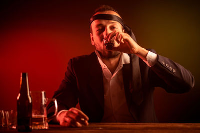 Portrait of a young man drinking glass on table