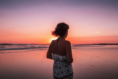 Rear view of woman looking at sea during sunset