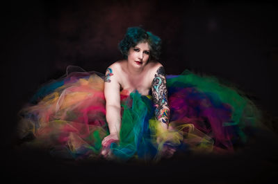 Portrait of woman with tattoo amidst tulle netting against black background