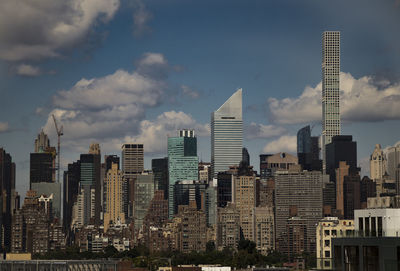 Buildings in city against cloudy sky