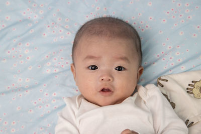 Portrait of cute baby lying on bed