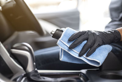 Midsection of man holding mobile phone in car