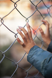 Midsection of man holding chainlink fence