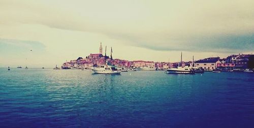 Boats in harbor against cloudy sky