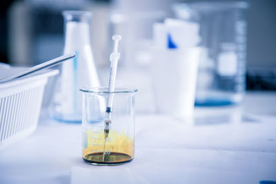 Close-up of syringe in beaker on table in laboratory