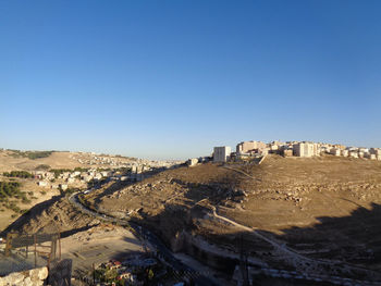 Built structure on landscape against clear blue sky