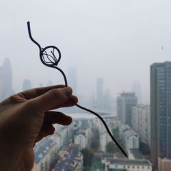 Person holding umbrella against buildings in city