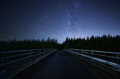 Footbridge and trees against star field at night