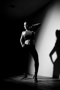 Full length of young woman dancing by wall in gym