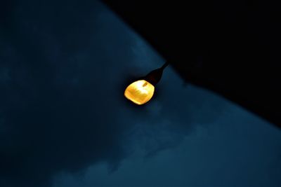 Low angle view of illuminated light bulb against sky