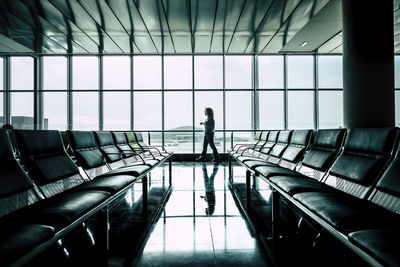 Side view of woman walking on floor by window at airport