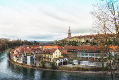Buildings by river against sky in city
