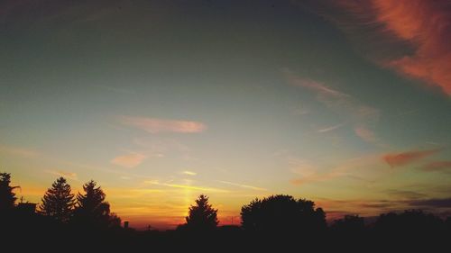 Silhouette trees against scenic sky