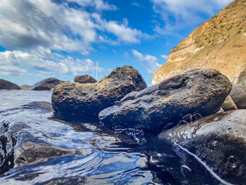 Rock formation on sea shore against sky